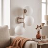 Moderna lampada da parete Gastor con tre sfere in vetro bianco, struttura sabbia